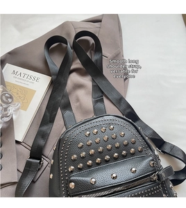 Detail of black pebbled leather backpack with silver rivets and smooth nylon shoulder strap