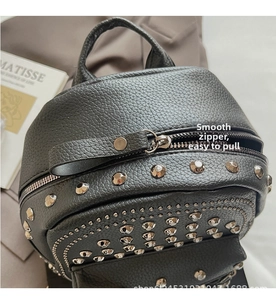 Detail view of black litchi texture leather backpack featuring silver rivet embellishments
