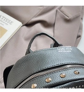 Close-up of black lychee grain leather backpack featuring silver studs and metal zipper
