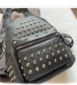 Close-up of soft black lychee grain texture and silver metal rivets on stylish backpack