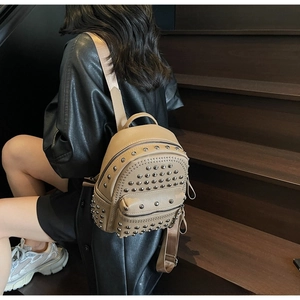 Detail of tan pebble leather backpack with silver studs on a wooden staircase