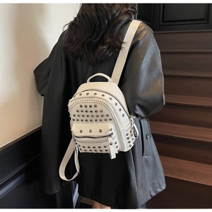 Close-up of white pebble leather backpack featuring silver metallic rivets and straps