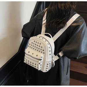 Detail of white mini backpack featuring silver metal studs on soft leather texture