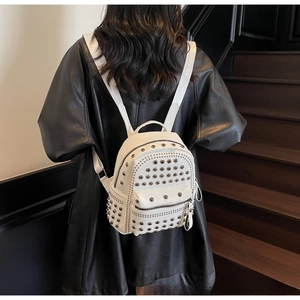 Detail shot of white leather backpack featuring decorative silver metal rivets and studs