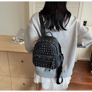 Side view of black studded leather backpack with silver rivets worn by a model