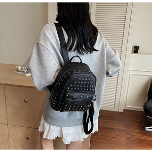 Close-up of black PU leather mini backpack featuring stylish metal rivets and zip pocket