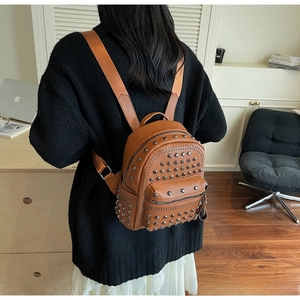 Close-up of brown pebbled leather mini backpack featuring silver studs and dual zippers