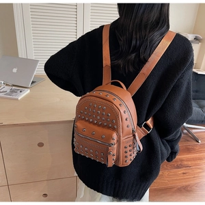 Detailed back view of a brown rivet mini backpack in pebbled leather on a model