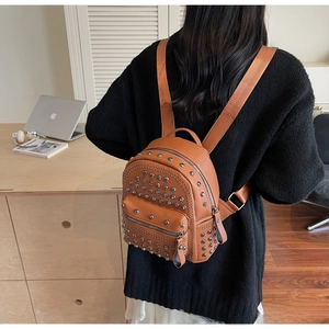 Close-up of brown pebbled faux leather mini backpack featuring silver rivet studs and zippers