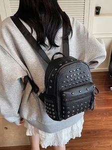 Fashionable black faux leather backpack with metallic rivets shown on a female model