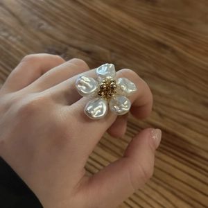 Detailansicht eines Blumenrings mit Barockperlen und Goldperlen auf Holzoberfläche