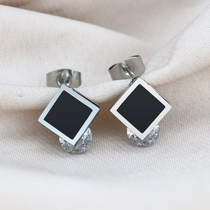 Square geometric silver earrings with black inlay and sparkling zircon on satin fabric
