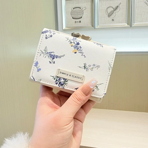 Close-up of floral trifold wallet with golden heart clasp and simple classic label
