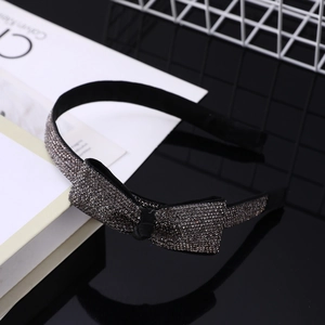 Dettaglio di un cerchietto nero con strass grigi e un fiocco di cristallo scintillante