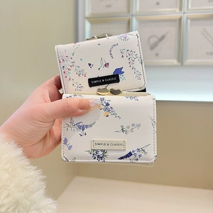 Detail view of floral print faux leather wallet with golden heart clasp and fabric label