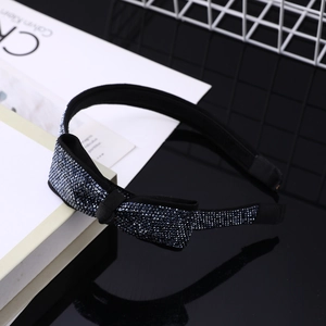 Dettaglio macro del cerchietto con strass blu navy scintillanti e un elegante fiocco