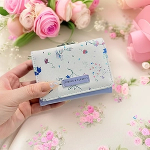 Detailed shot of a floral tri-fold wallet held against fresh roses and white flowers