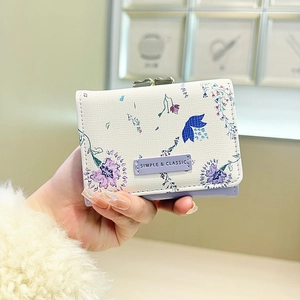 Close-up of a floral tri-fold wallet featuring purple prints and metal clasp closure