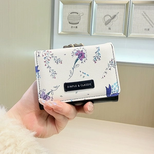 Handheld view of cream-colored floral tri-fold wallet with elegant purple flower patterns