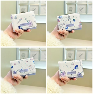 Detail of floral trifold wallet with vintage metal buckle and a white leather texture