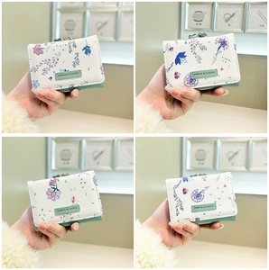 Close-up of trifold floral wallet featuring vintage metal clasp and elegant logo detail