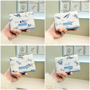 Close-up of floral print mini wallet with blue trim and Simple & Classic leather label