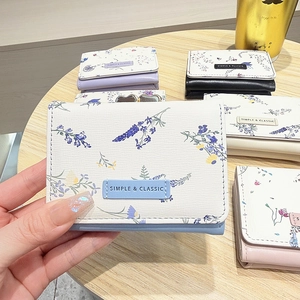 Close-up of compact tri-fold floral wallet featuring elegant lavender patterns and texture