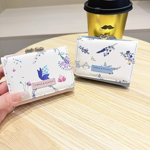 Close-up of floral print mini wallets with heart metal buckle and leather logo tag