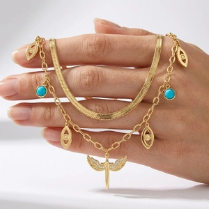 Close-up of layered 18K gold snake chain necklace with turquoise and wing sword pendant
