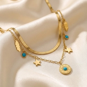 Detail of layered gold stainless steel necklace with turquoise evil eye and star charms