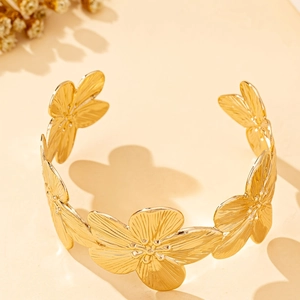 Detail of golden floral open cuff bracelet showing brushed petal texture and beads