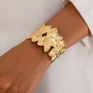 Detailed close-up of golden leaf wide open bangle with textured vein patterns on model