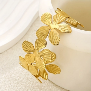 Detail of golden floral open cuff bracelet with textured petals on ceramic base