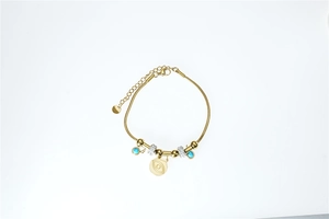 Detailed view of gold snake chain bracelet with blue beads and evil eye pendant charm