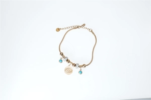 Detail of gold snake chain bracelet with blue turquoise charms and evil eye pendant
