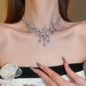 Close-up of floral zircon necklace with teardrop pendants on female model