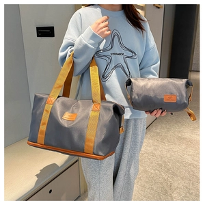 Detail of grey waterproof nylon travel bag set with bright orange handles and brand tags