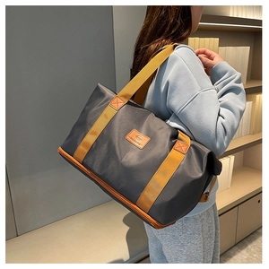 Detail view of the deep grey nylon travel bag showing the bottom expansion zipper layer