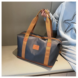 Detail of gray travel bag with durable brown handles and reinforced stitching for gym and travel
