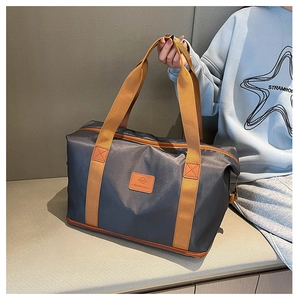Detail view of large travel bag with orange straps and leather fashion label decoration