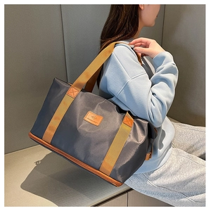 Detail of waterproof nylon travel bag with wide orange straps and reinforced zipper stitching