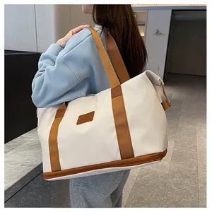 Rear view of a model carrying a white travel bag with brown straps in a modern hallway