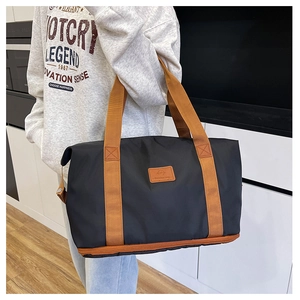 Detail of reinforced orange webbing handles on black nylon large travel tote bag