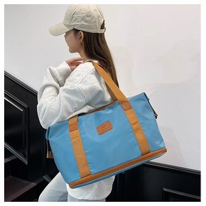 Detail of light blue travel bag featuring brown straps and separate bottom shoe compartment