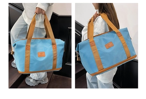 Macro detail of the stylish sky blue travel tote with brown webbing straps and logo patch