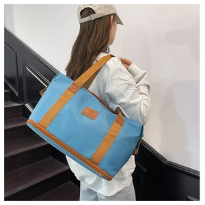 Detail of expandable blue travel bag featuring brown straps and reinforced bottom base