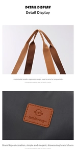 Detail of woven brown handles and leather logo patch on a grey large travel bag