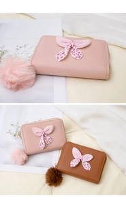 Detail of bow-knot design and fluffy pompom charm on short PU leather wallets for women