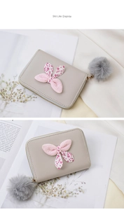 Detail of grey PU leather mini wallet with pink polka dot bow and faux fur pompom charm