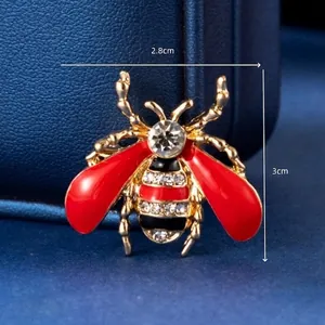 Macro shot of a bee brooch with red oil drop wings and crystals, size 2.8x3cm